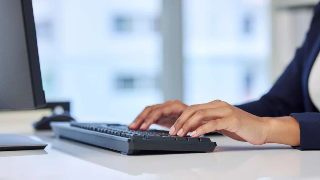 2 - Gambar seseorang sedang mengetik sesuatu dengan keyboard di depan komputer
