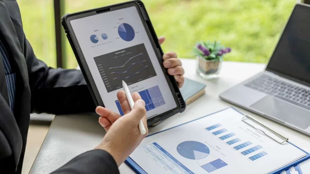 4 - gambar ilustrasi penjualan yang ditunjukkan oleh seseorang pada tablet yang menampilkan chart