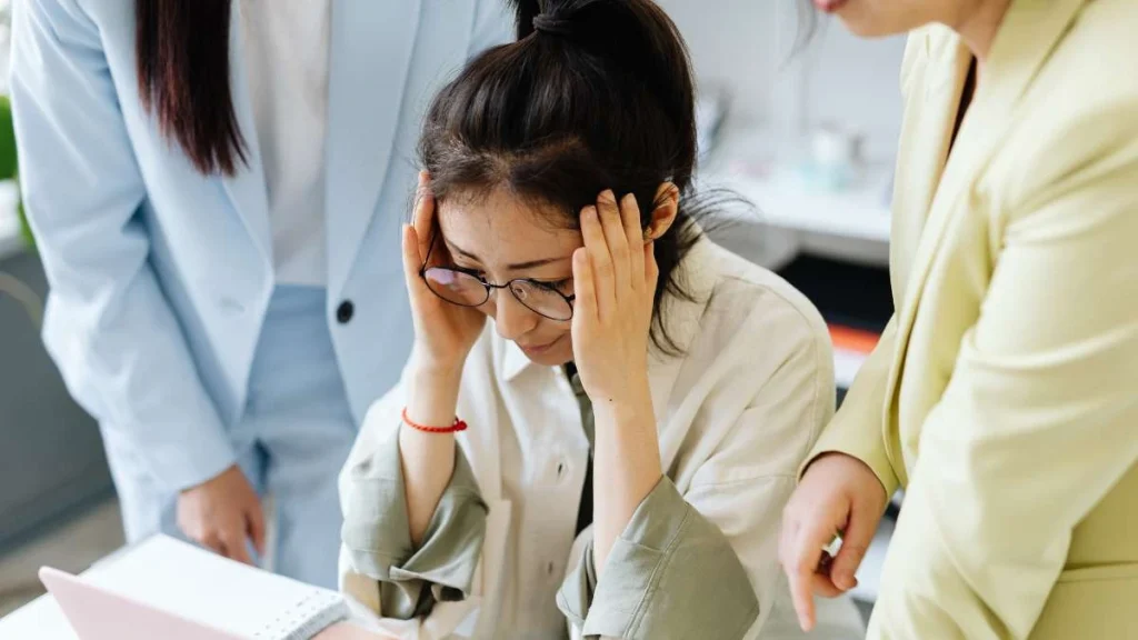 5 - Gambar seorang wanita memegang kepala berada di antara dua orang