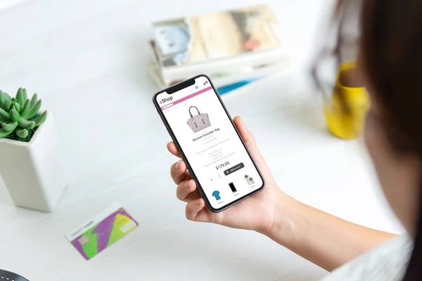 Seseorang sedang mempertimbangkan membeli tas di online shop