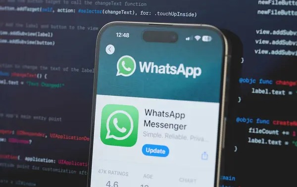 Aplikasi WhatsApp di layar HP dengan background coding