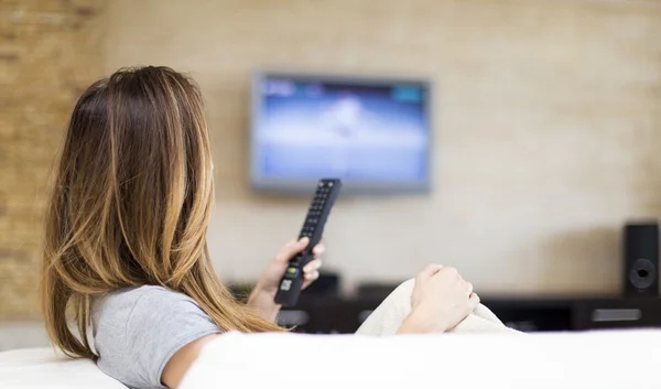 Seseorang sedang menonton TV sambil memegang remot