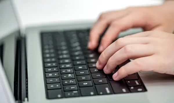 Seorang staf sedang mengetik pesan di laptop